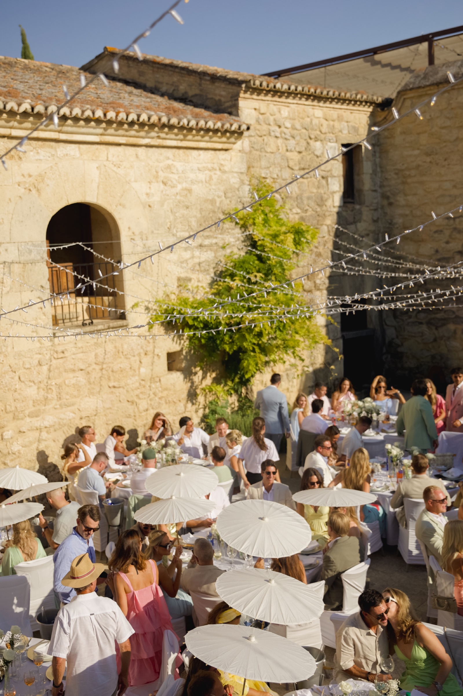 Guests under white parasols at a daytime reception